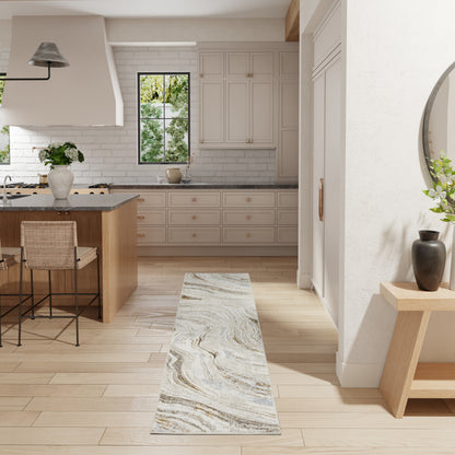 Modern kitchen with light wood floors, gray shaker cabinets, marble countertops, island with woven stools, marble runner rug.