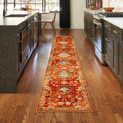 Persian-style runner rug in red, orange and cream on hardwood kitchen floor between dark gray cabinets.