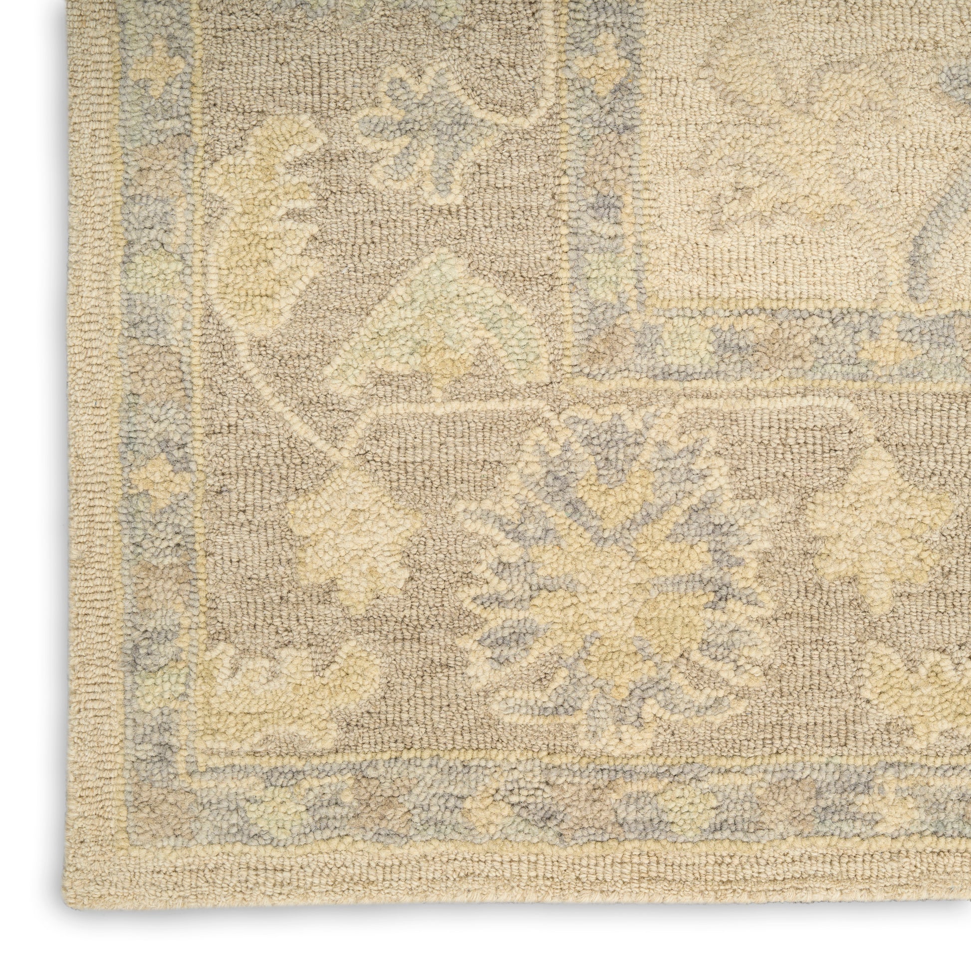Beige and pale blue oriental area rug corner with floral medallion, woven texture and fringe border.