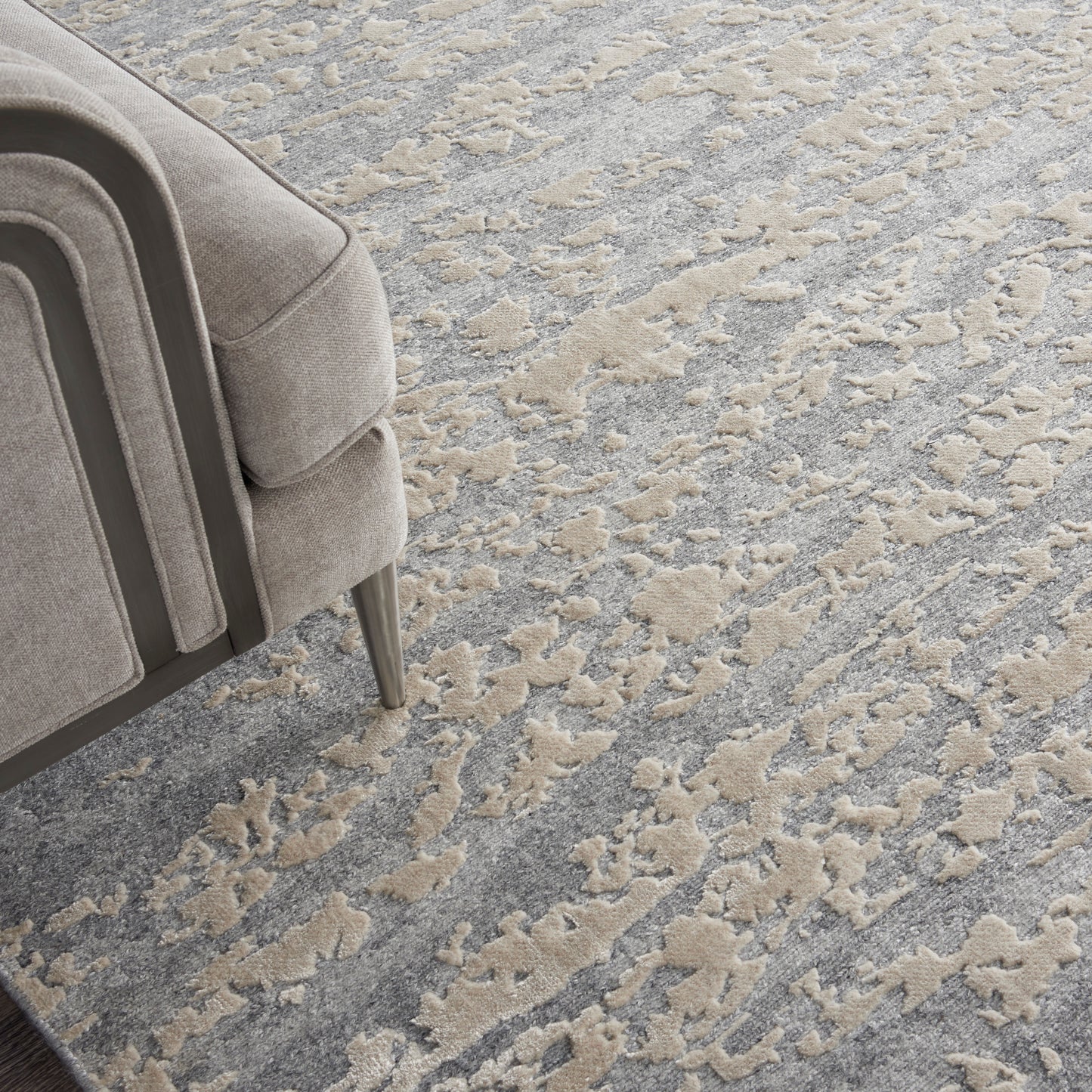 Light gray fabric sofa with metal legs & curved cushions on a beige-gray abstract patterned rug.