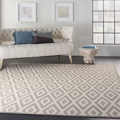 Cream-toned mid-century modern rug with a subtle geometric pattern in a living room scene, paired with a carved side table with books, framed art, and a grid-window view.