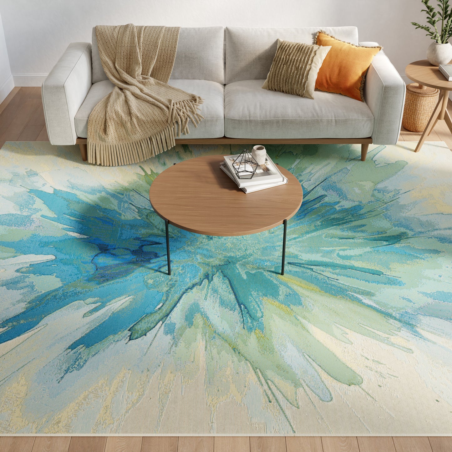 Living room with round wooden coffee table on a blue-green abstract rug, gray sofa, beige throw, and orange pillows.
