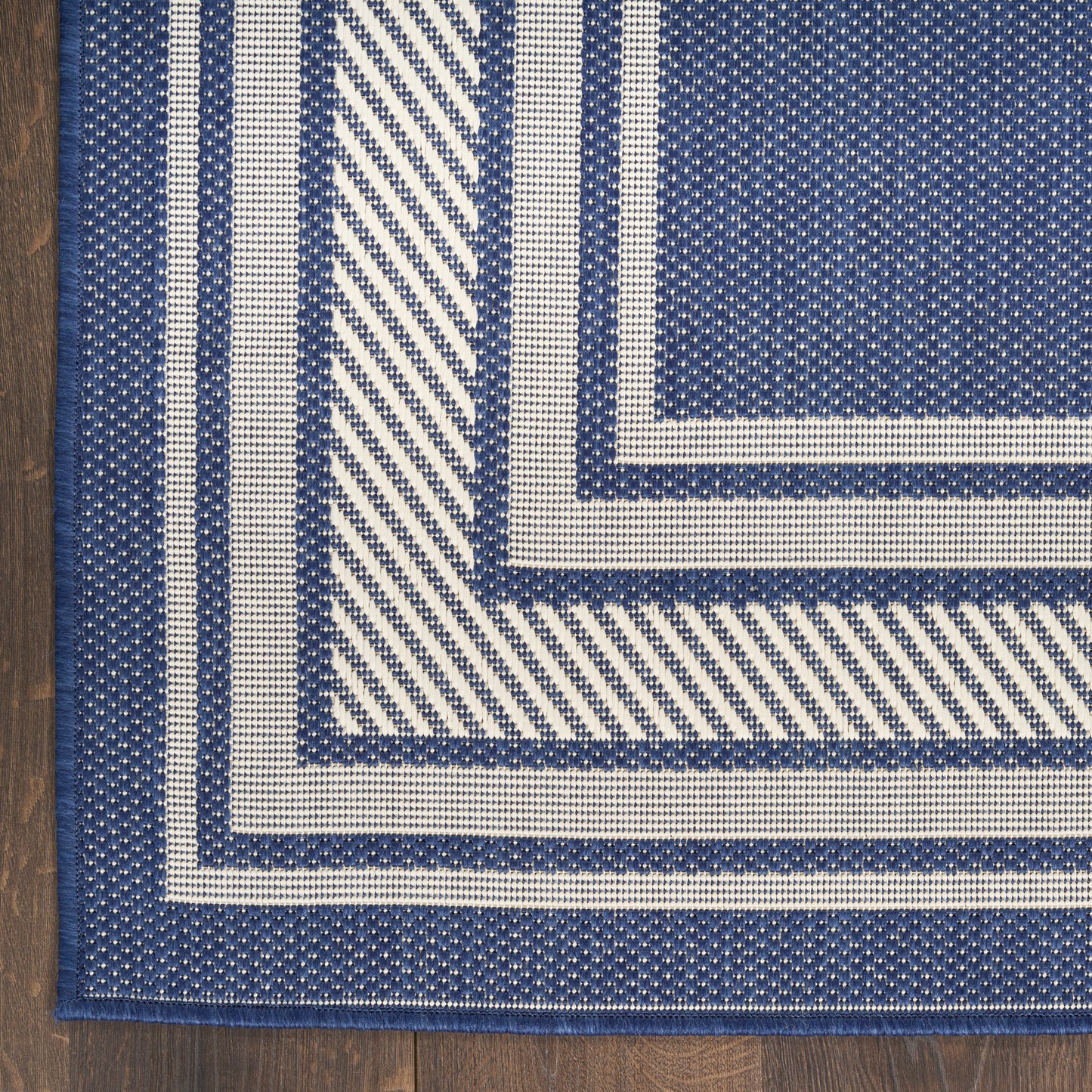 Navy blue and cream woven rug with outer concentric borders and diagonal stripe accents; nautical geometric rug.
