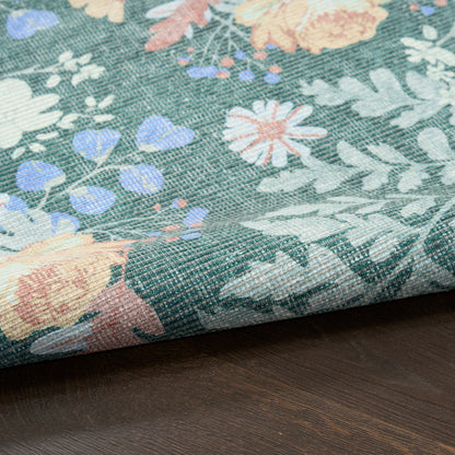 Floral rug with teal background & pastel pink, peach, white, and blue flowers; folded edge visible on dark wood surface; 4' x 6'.