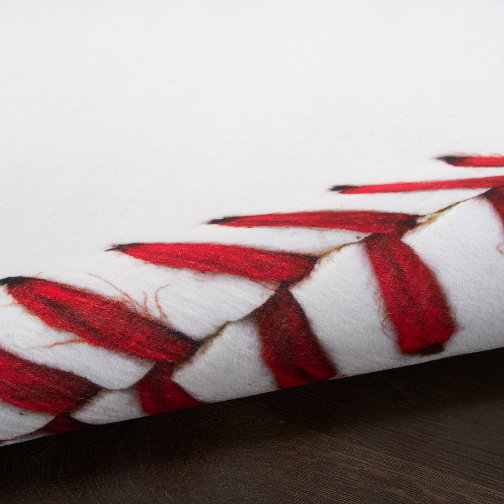 Round white rug with red braided tassel trim around the edge, laid on dark wood surface, 5' round.