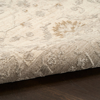Beige floral patterned area rug with plush pile; rolled edge shows thickness on dark wood floor.