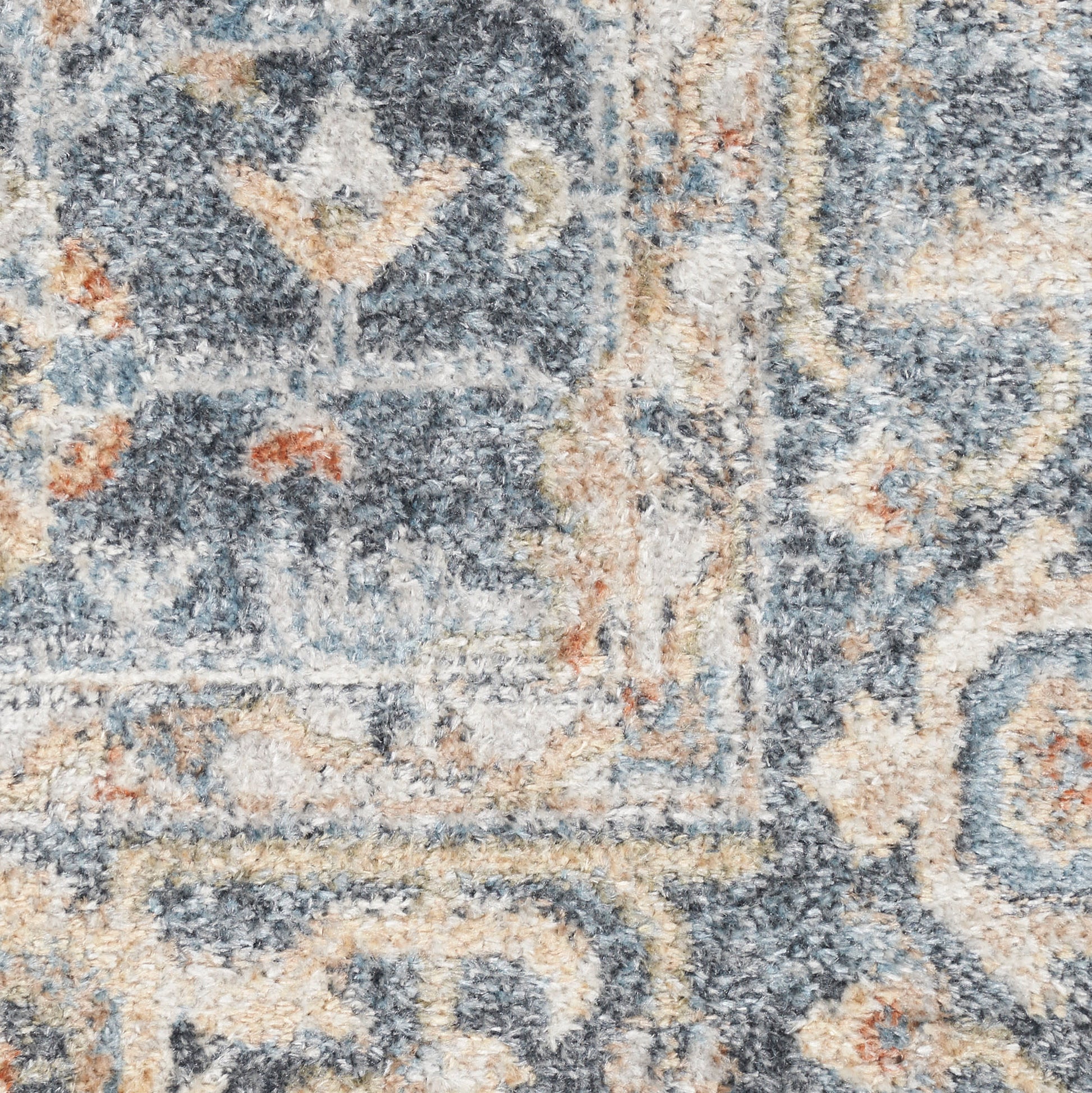 Close-up of a blue-gray and beige patterned area rug with intricate floral-geometric motifs and a plush pile.