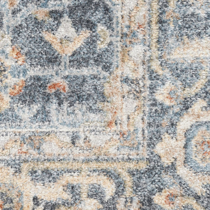 Close-up of a blue-gray and beige patterned area rug with intricate floral-geometric motifs and a plush pile.