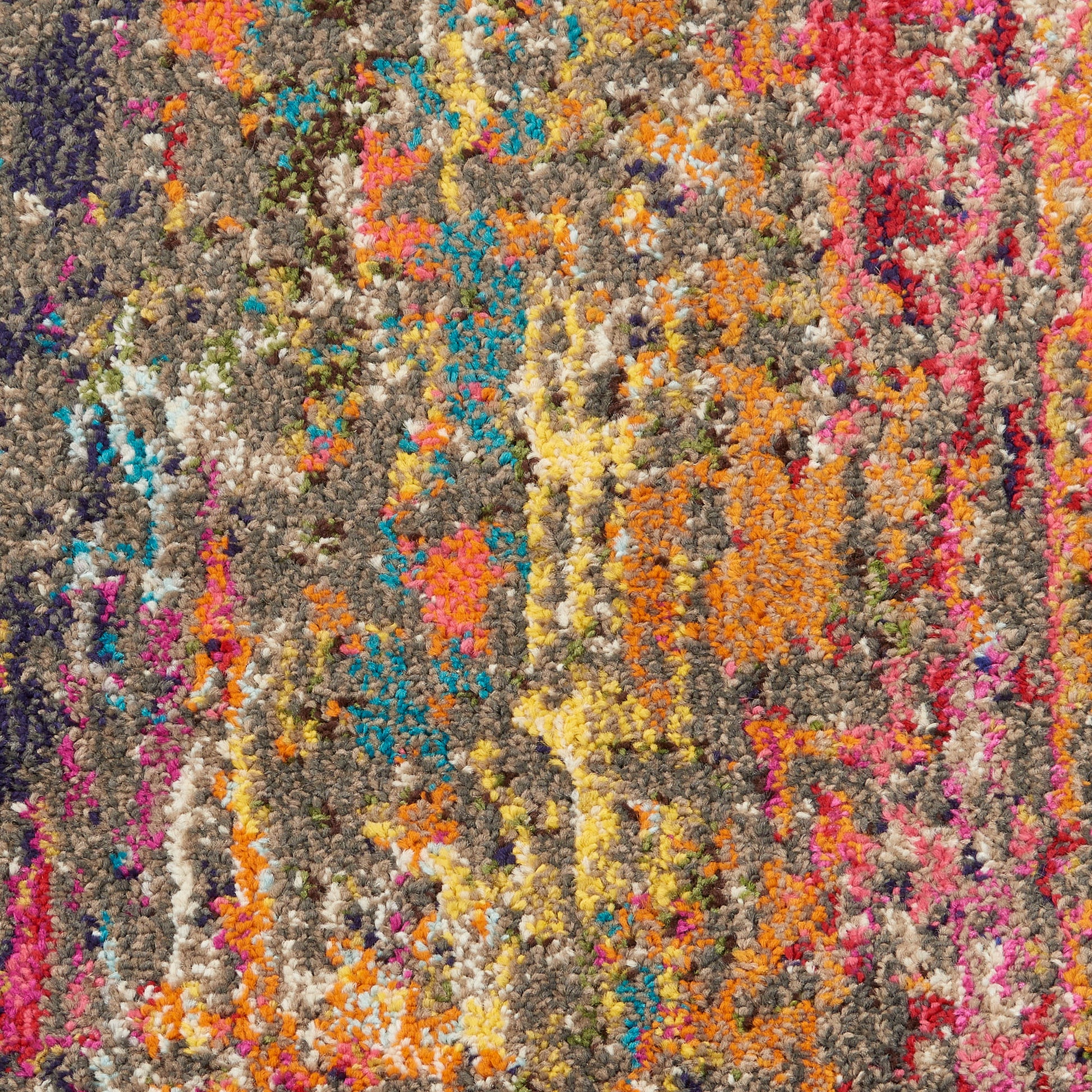 Close-up of a chunky multicolor shag rug with orange, yellow, pink, blue and purple tufts on a gray base.