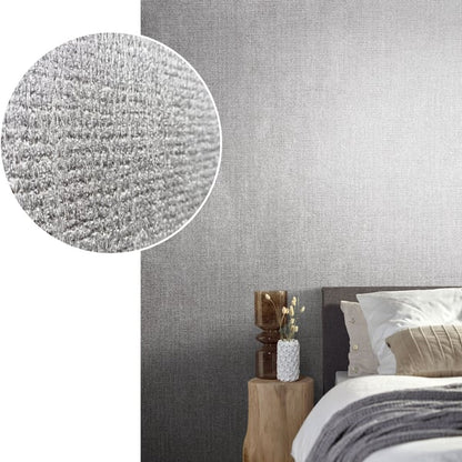 Grey textured wallpaper gradient behind a modern bed with white bedding, beige throw, and a natural wood bedside table.