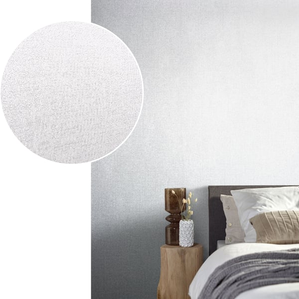 Bedroom scene with silver-grey wallpaper on the wall behind a gray upholstered headboard, beige cushions, and a wooden stump nightstand with a white textured vase.