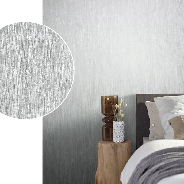 Bedroom with brushed silver-grey textured wallpaper, dark headboard, wooden nightstand, white vase and dried stems.