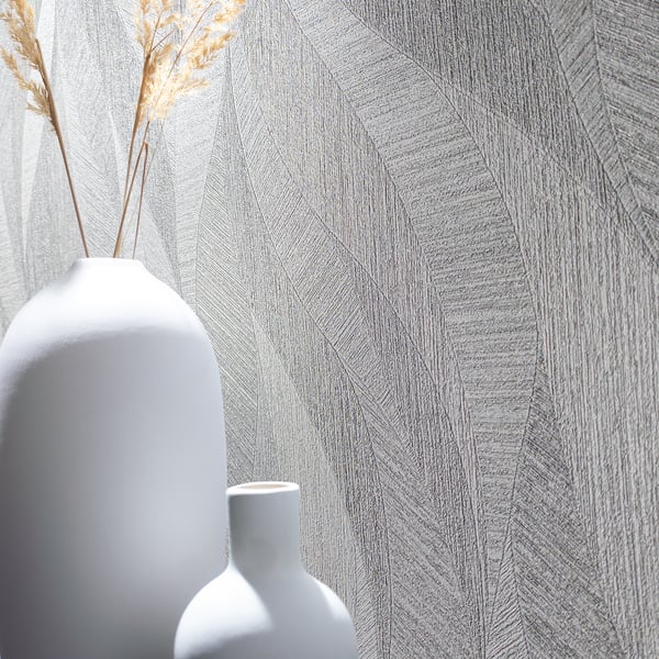 Gray geometric wallpaper with a textured pattern; two white ceramic vases (a tall rounded vase with dried grasses and a smaller one) in front.