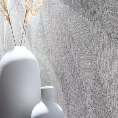 Gray geometric wallpaper with a textured pattern; two white ceramic vases (a tall rounded vase with dried grasses and a smaller one) in front.