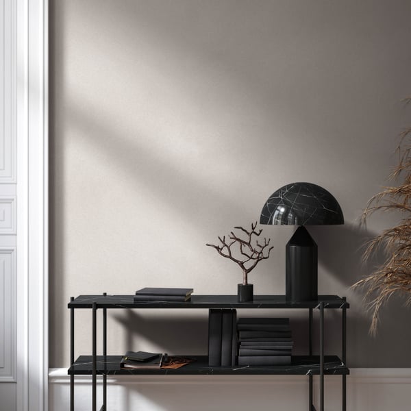Black metal two-shelf console against beige wall with veined black glass dome lamp, black tree sculpture, and dark books.
