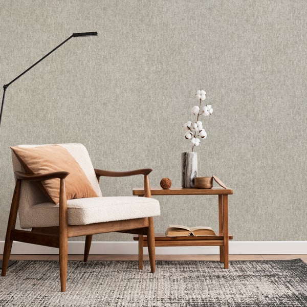 Beige textured wallpaper on wall; room scene includes a mid-century beige upholstered armchair with an orange pillow, oak side table, vase of white flowers, and an arc floor lamp.