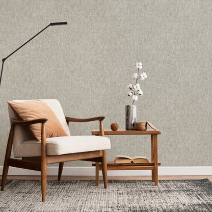 Beige textured wallpaper on wall; room scene includes a mid-century beige upholstered armchair with an orange pillow, oak side table, vase of white flowers, and an arc floor lamp.
