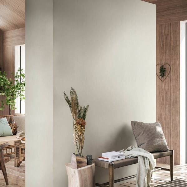 Neutral beige wallcovering in a warm, modern living space; wooden bench with a pillow, throw, and a vase of dried grasses.