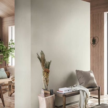 Neutral beige wallcovering in a warm, modern living space; wooden bench with a pillow, throw, and a vase of dried grasses.