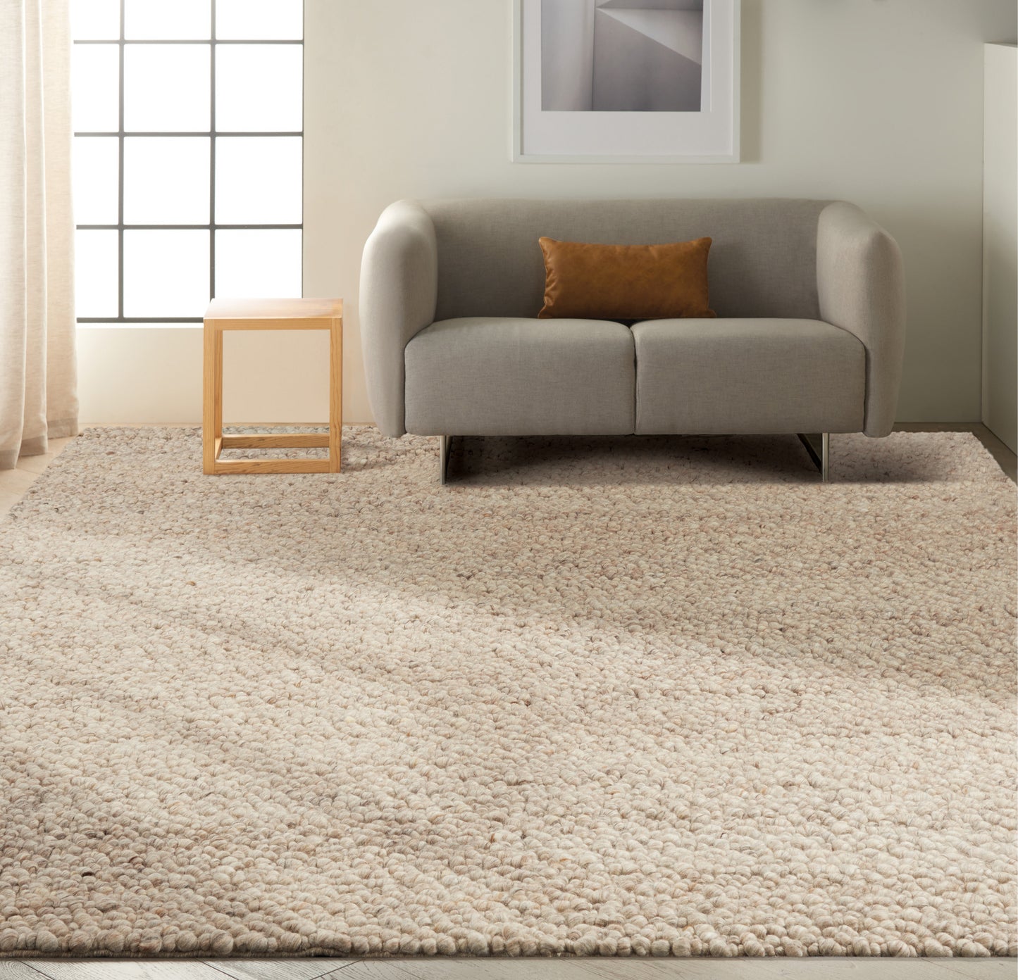 Light gray fabric loveseat with brown throw pillow, wooden cube side table, beige shag rug, grid window & framed art.