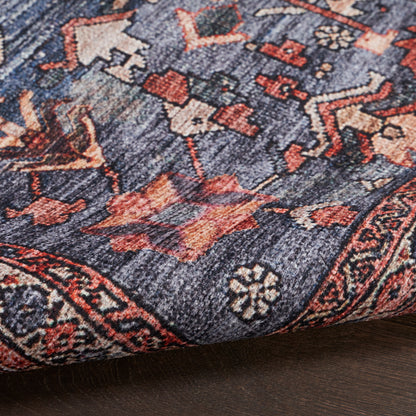 Blue and navy oriental rug with red and ivory floral motifs, traditional Persian pattern, folded corner on wood floor.