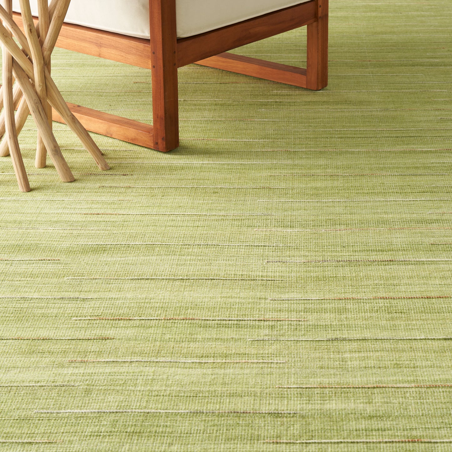 Light-green textured rug with subtle horizontal lines beneath honey wood chair legs and beige upholstery.