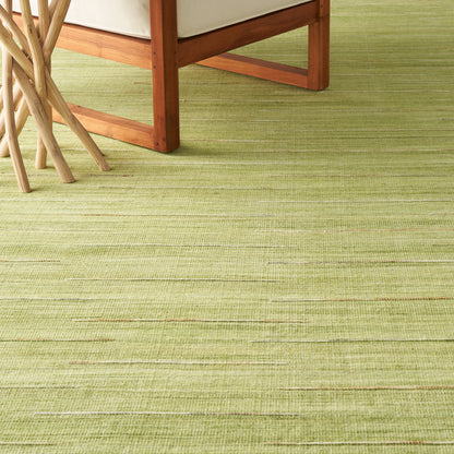Light-green textured rug with subtle horizontal lines beneath honey wood chair legs and beige upholstery.