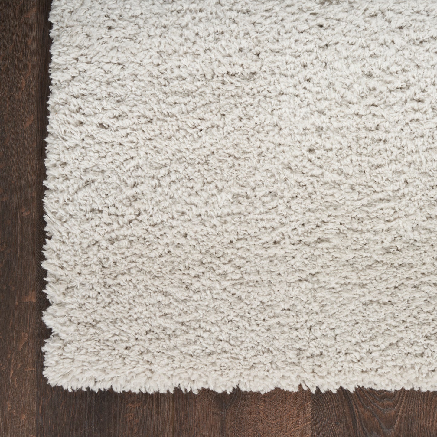Cream high-pile shag rug on dark wood floor; plush, fluffy texture and rectangular cozy living-room style.