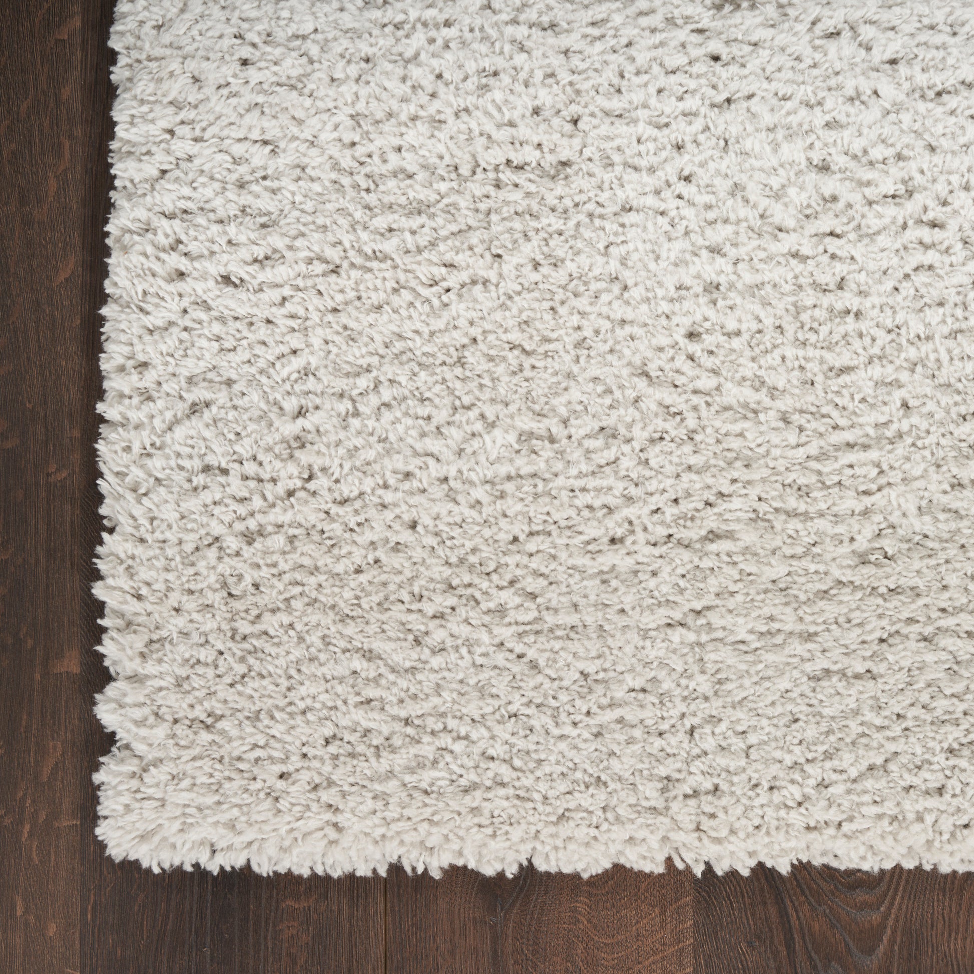Cream high-pile shag rug on dark wood floor; plush, fluffy texture and rectangular cozy living-room style.
