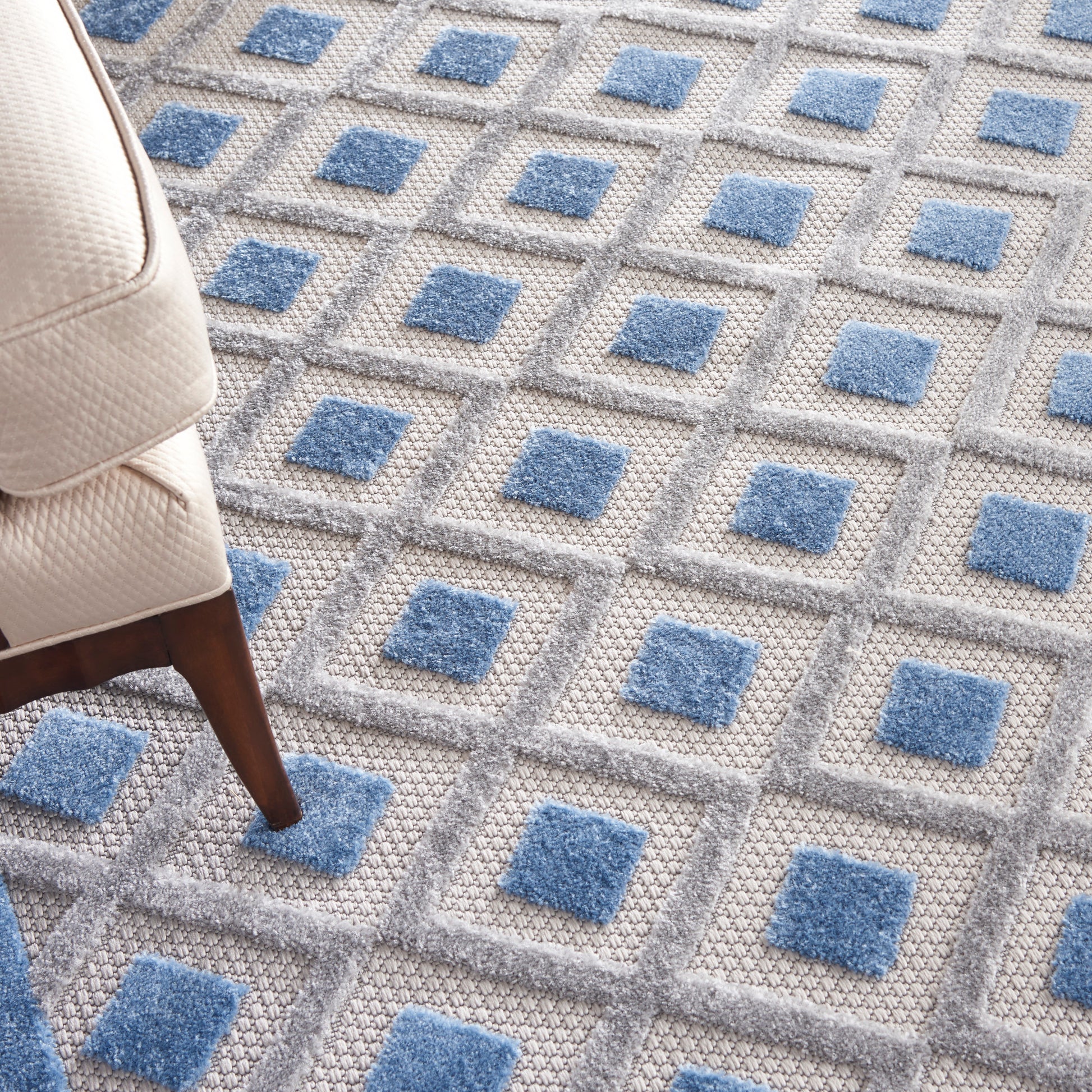 Gray textured rug with blue square accents in a geometric grid.