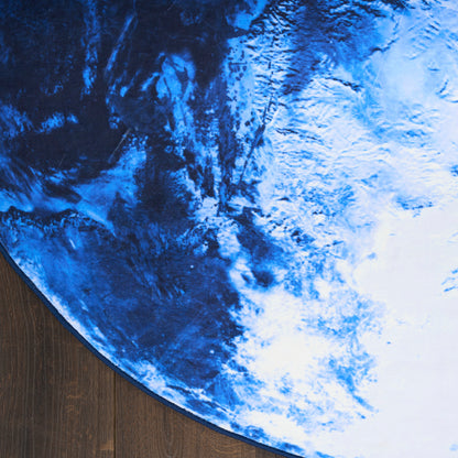 Round blue and white Earth-pattern rug on dark wood floor, space-inspired home decor.