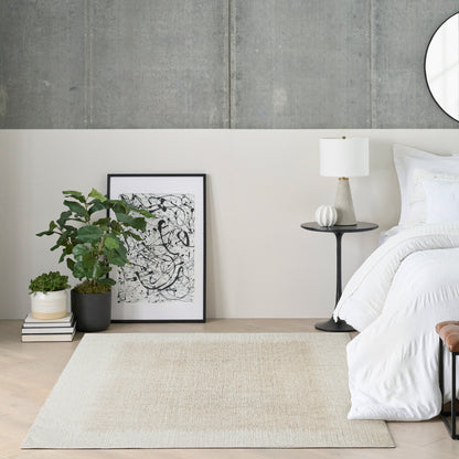 Minimalist bedroom corner: concrete wall, white bedding, black side table with lamp, abstract art, potted plants, beige rug