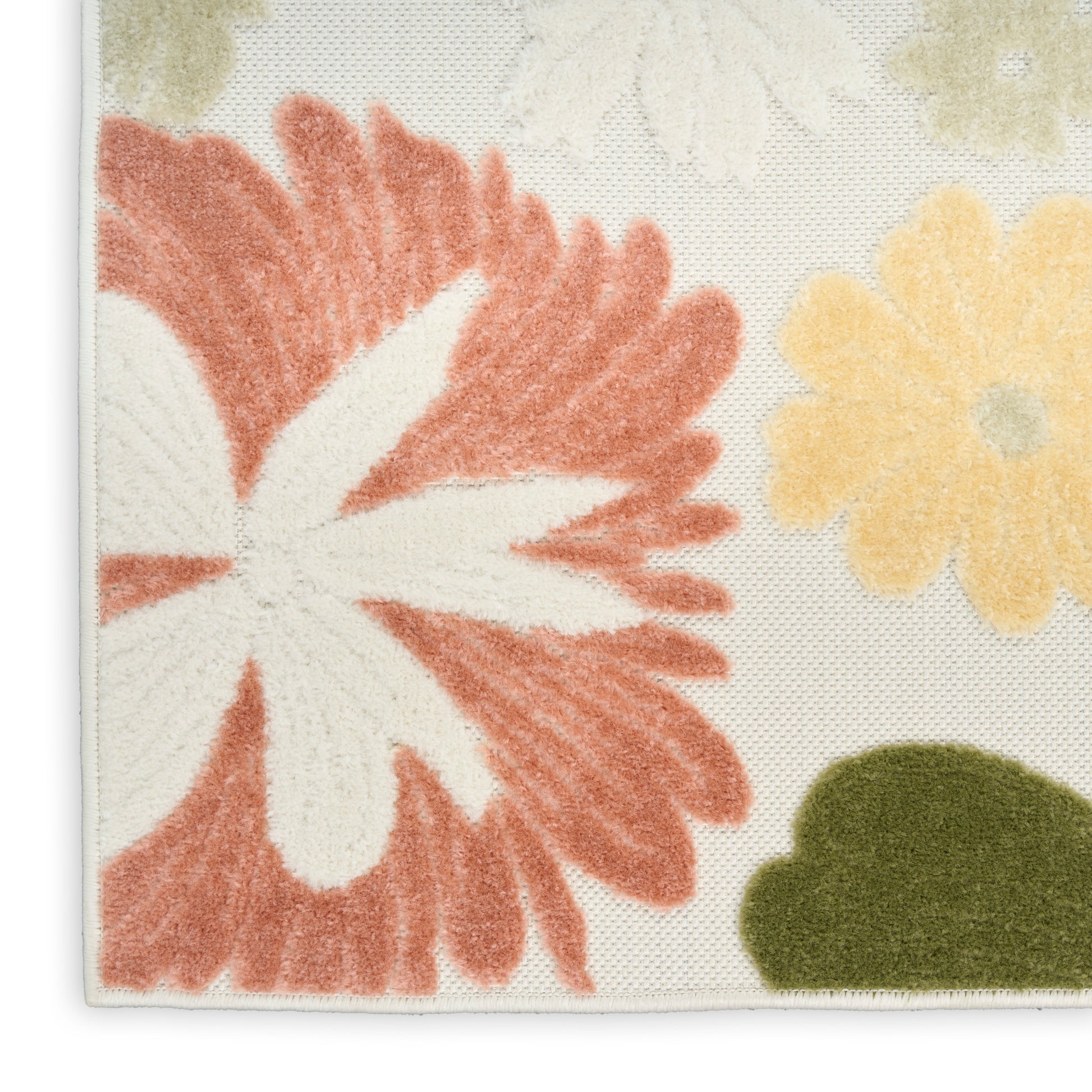 Close-up of a tufted floral rug with coral petals, pale yellow flowers and green accents on a cream background, stitched edge.
