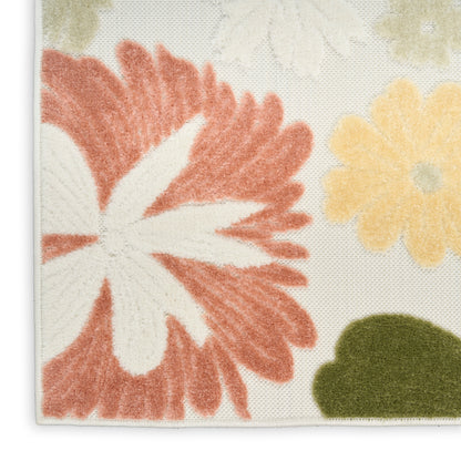 Close-up of a tufted floral rug with coral petals, pale yellow flowers and green accents on a cream background, stitched edge.