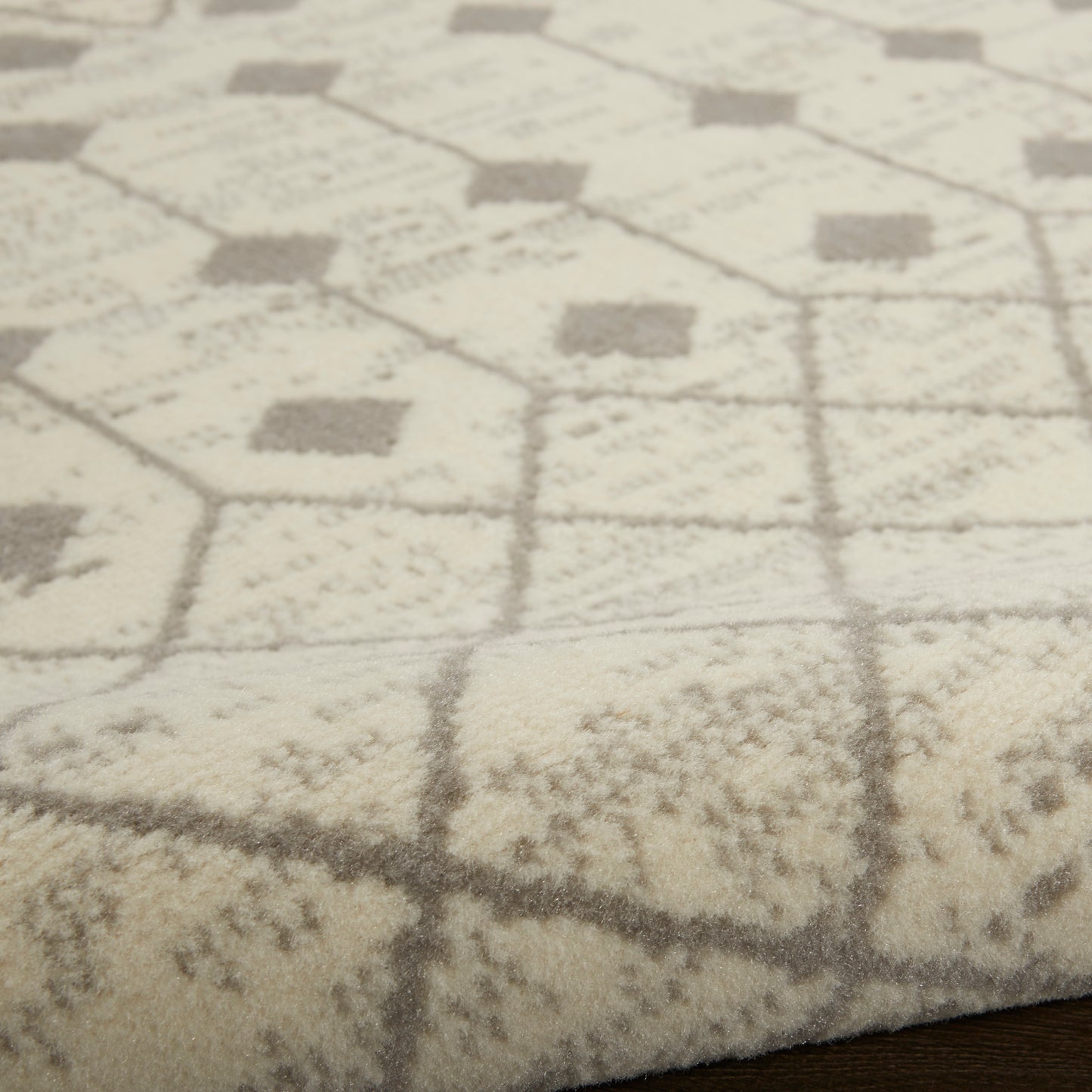 Cream and gray plush area rug with hexagon and diamond geometric pattern on a wood floor.