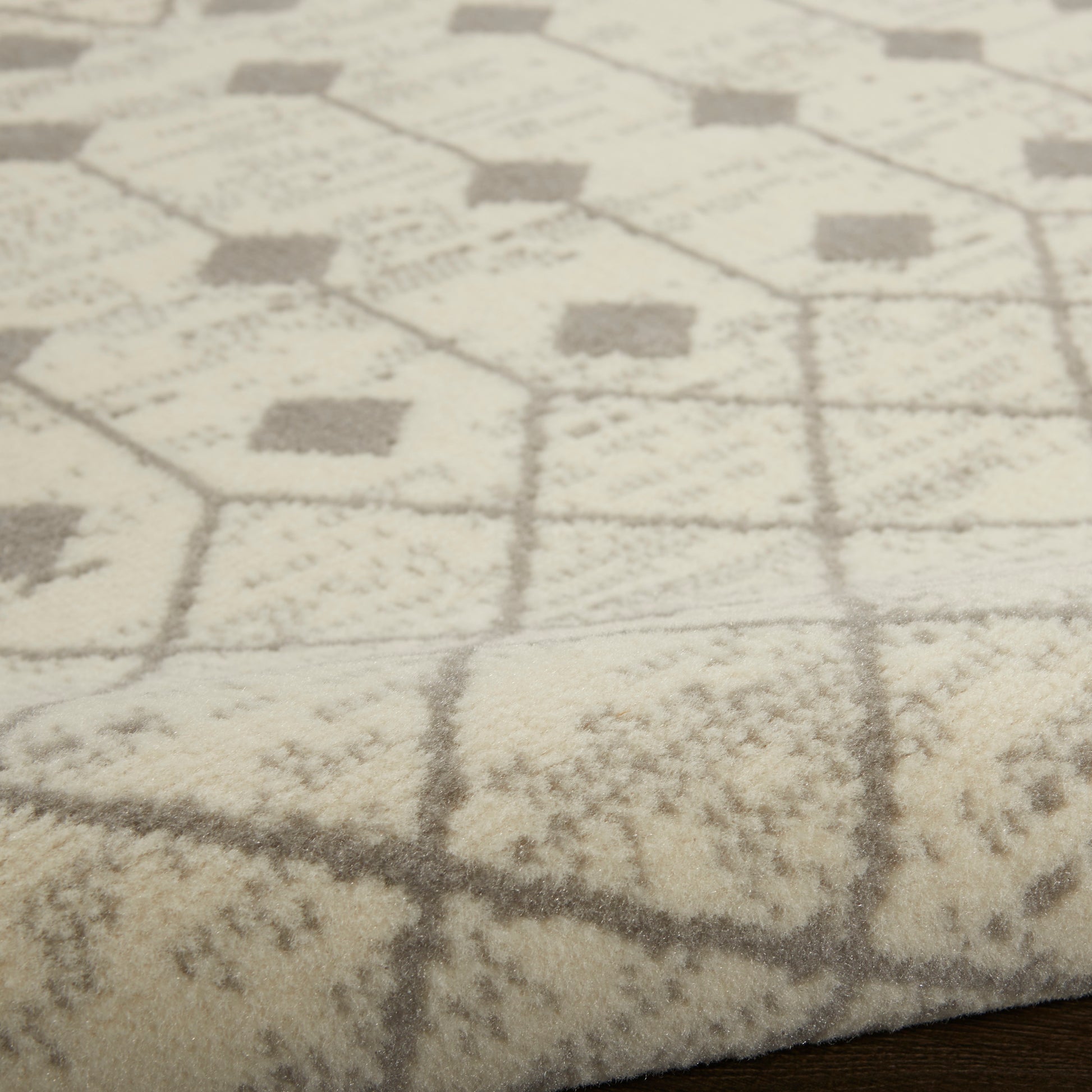 Cream and gray plush area rug with hexagon and diamond geometric pattern on a wood floor.