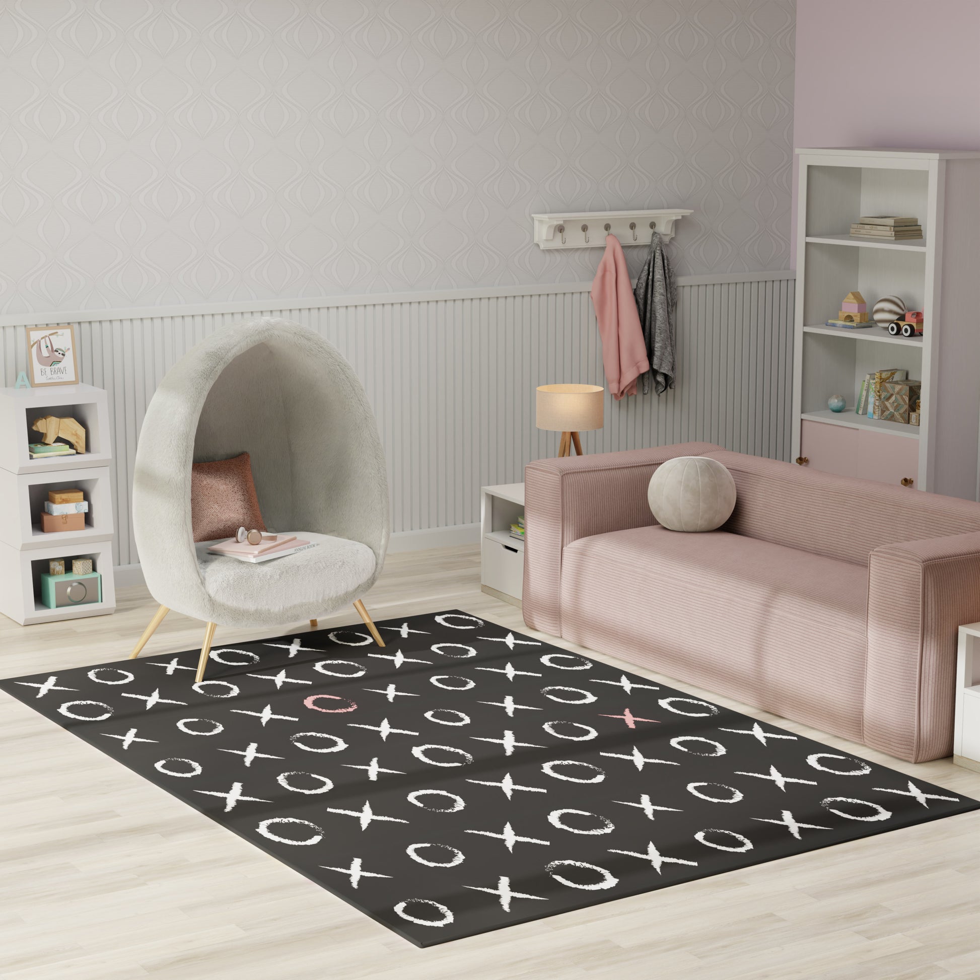 Cozy kids' lounge with pink sofa, plush grey egg chair, black X-O patterned rug, white shelves, pastel accents.