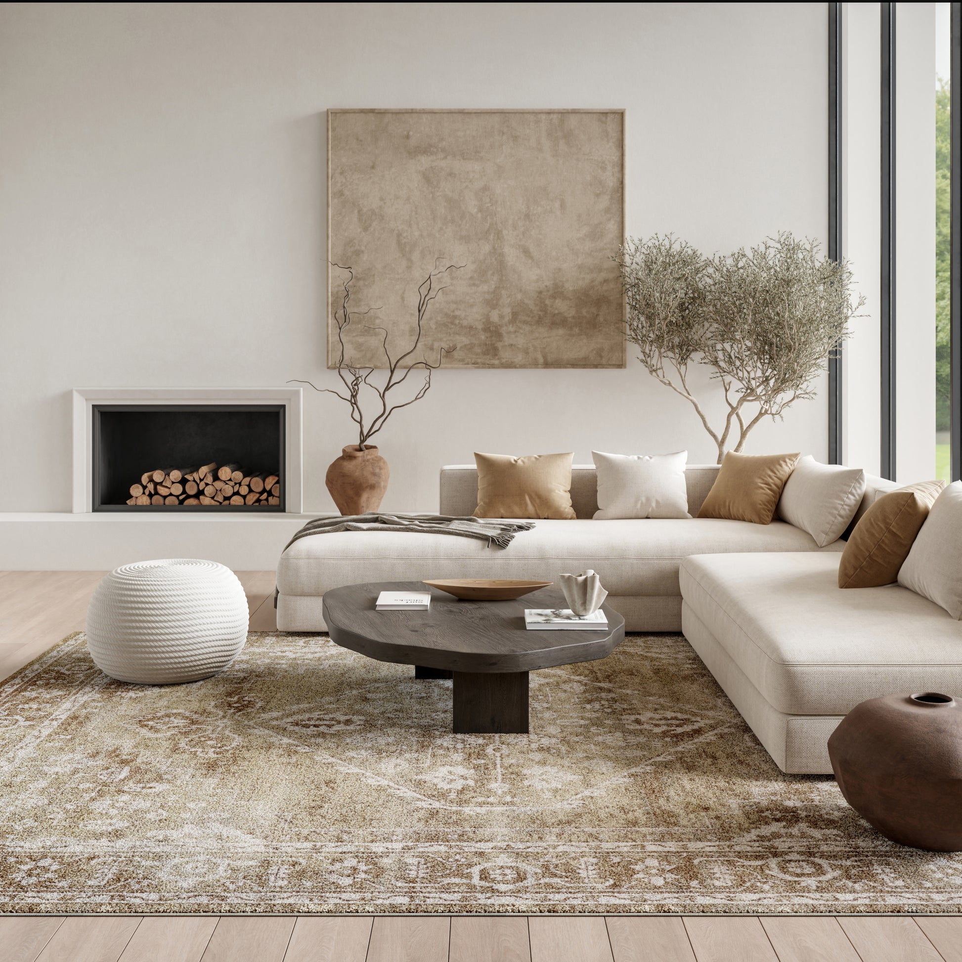 Neutral living room featuring a beige sectional, round dark wood coffee table, textured beige rug, white knitted pouf, and tall trees by a large window.