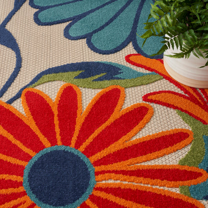 Bright multicolor floral rug with orange-red petals, navy center, lime leaves on beige woven background.