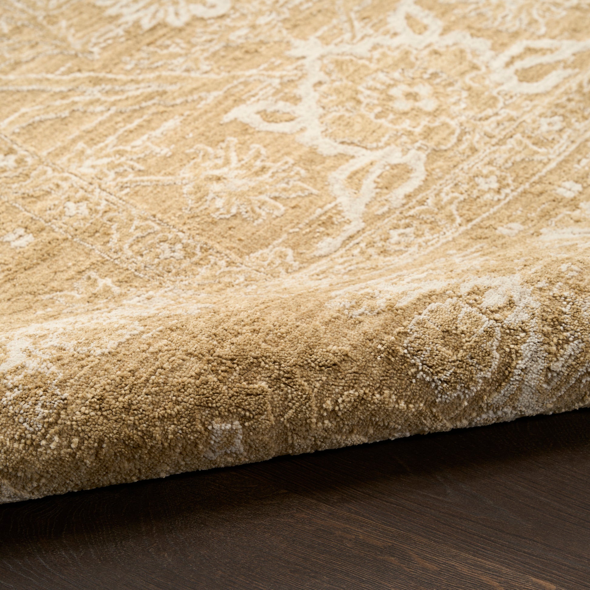 Beige patterned rug with floral motif, thick plush pile and rolled edge on dark wood floor