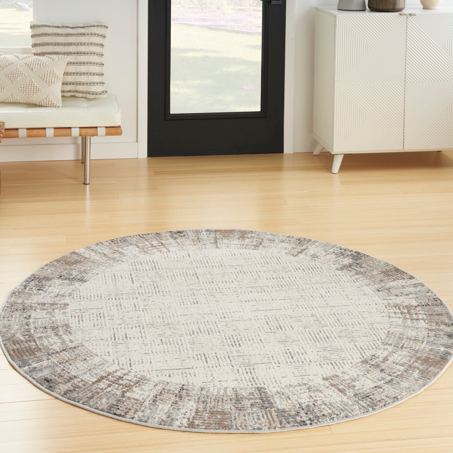 Round gray-beige rug on light wood floor in a modern living room.