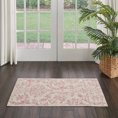 Pink damask patterned area rug on dark wood floor in front of glass French doors; potted palm in a woven basket nearby.