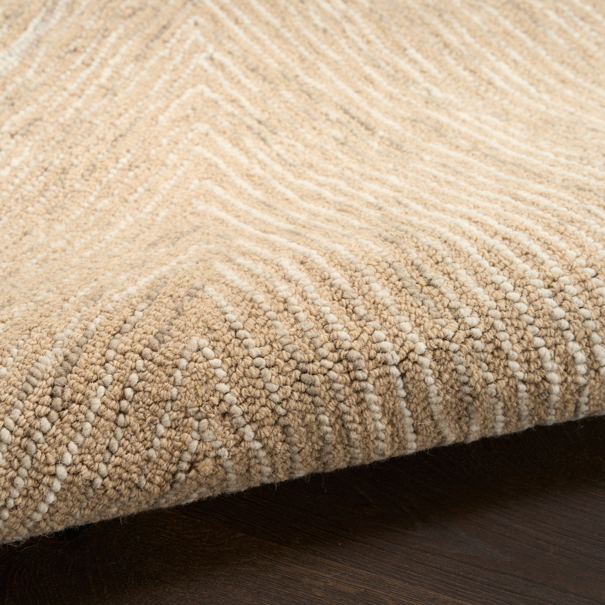 Beige textured runner rug with chevron looped pile and folded edge on dark wood floor