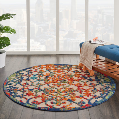 Round multicolor ornate-pattern rug with blue edge on dark wood floor in a bright modern living room.