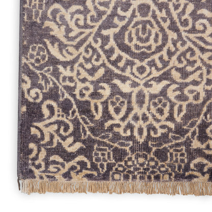 Purple woven rug with beige damask floral pattern and a fringed edge.