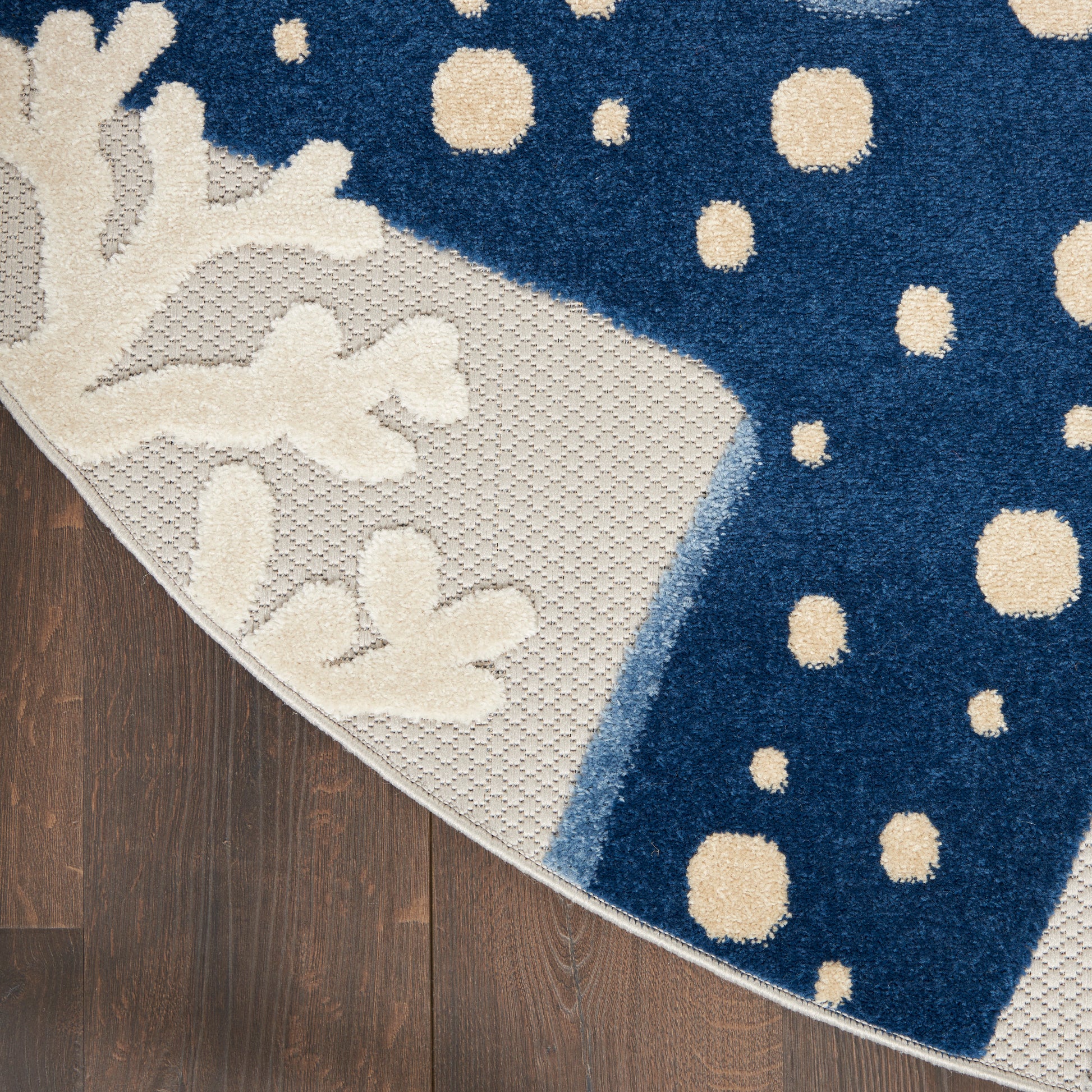 Circular navy rug with cream botanical pattern and textured border on dark wood floor.
