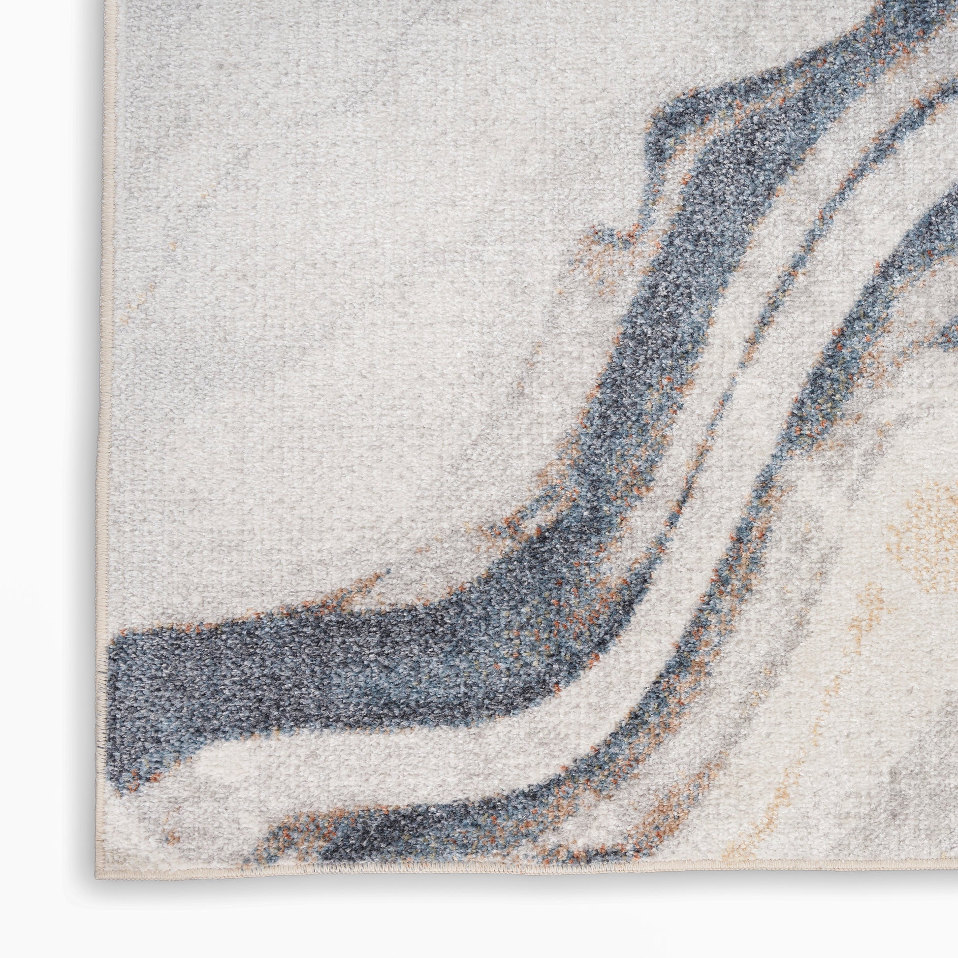 Close-up of an abstract textured rug with flowing blue and beige waves on cream background, edge visible.