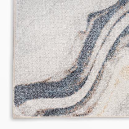 Close-up of an abstract textured rug with flowing blue and beige waves on cream background, edge visible.