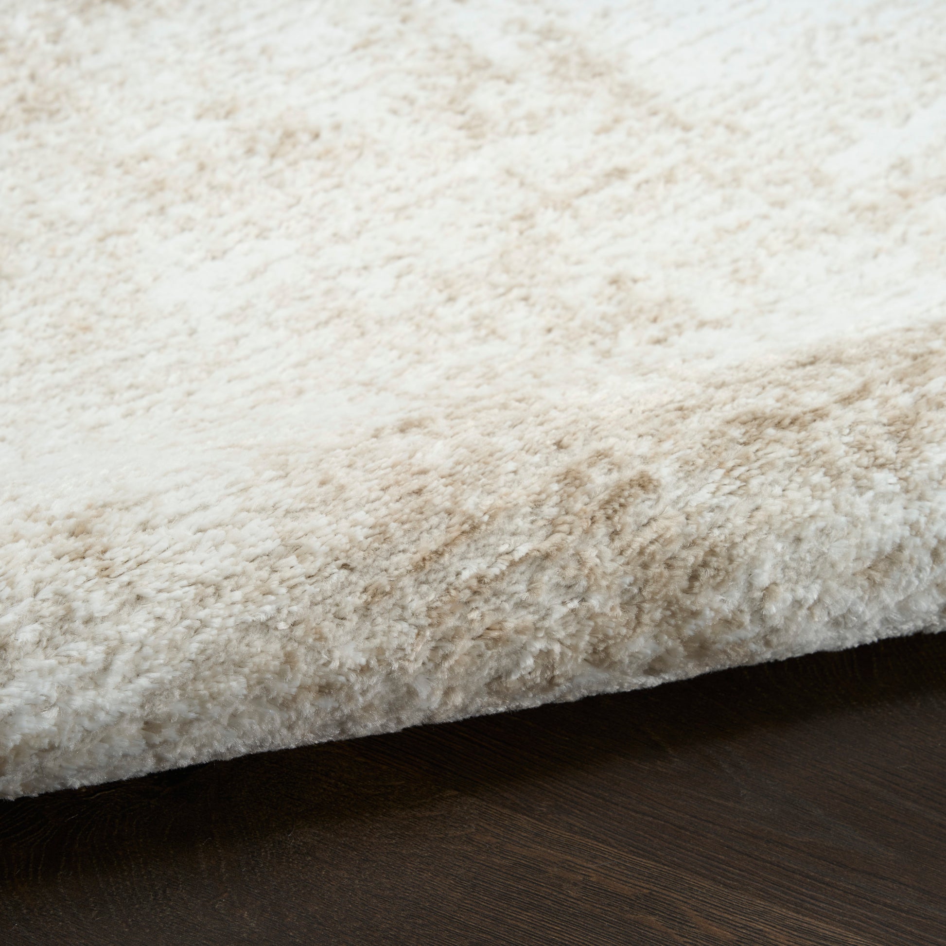 Cream shag rug with plush high-pile texture and visible edge on dark wood floor.