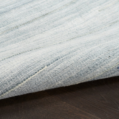 Light blue textured fabric with visible weave and seam, draped over dark wooden surface.